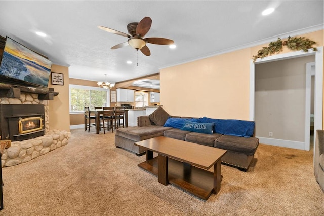 carpeted living room featuring crown molding, a fireplace, and ceiling fan with notable chandelier