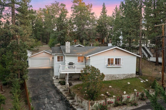 ranch-style home featuring a yard, a garage, and a deck