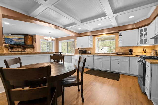 kitchen featuring stainless steel gas stove, white cabinetry, light stone counters, decorative light fixtures, and dishwasher