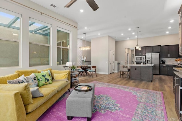 16750 Coyote Bush Dr Unit 107, San Diego, CA 92127 - living room featuring visible vents, baseboards, wood finished floors, recessed lighting, and ceiling fan with notable chandelier