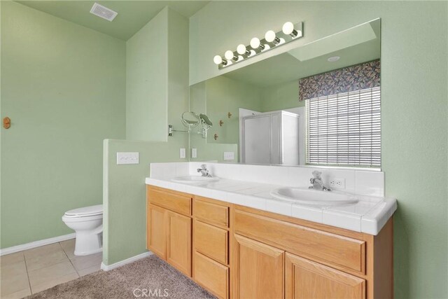 bathroom with vanity, toilet, a shower with shower door, and tile patterned flooring