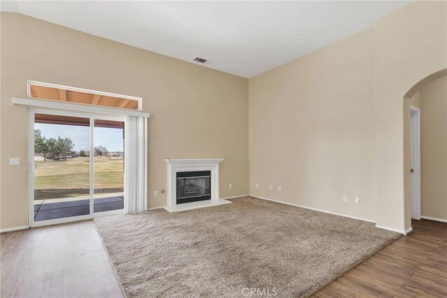 unfurnished living room with hardwood / wood-style flooring and vaulted ceiling