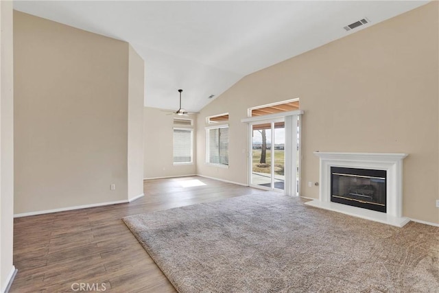 11262 Country Club Dr, Apple Valley, CA 92308 - unfurnished living room with visible vents, a glass covered fireplace, wood finished floors, ceiling fan, and vaulted ceiling