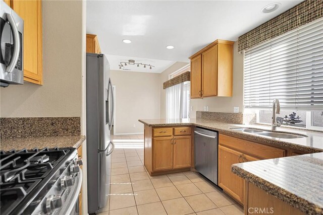 kitchen with light tile patterned flooring, rail lighting, sink, kitchen peninsula, and stainless steel appliances