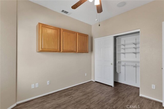 unfurnished bedroom featuring ceiling fan, dark hardwood / wood-style flooring, and a closet