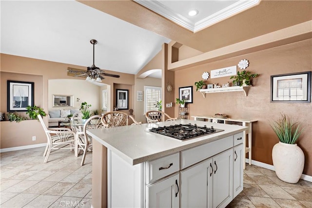 kitchen featuring stainless steel gas stovetop, white cabinetry, lofted ceiling, a center island, and crown molding