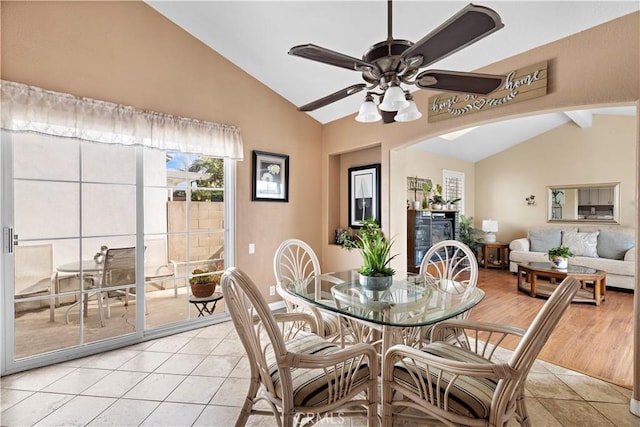 tiled dining area with ceiling fan and lofted ceiling with beams