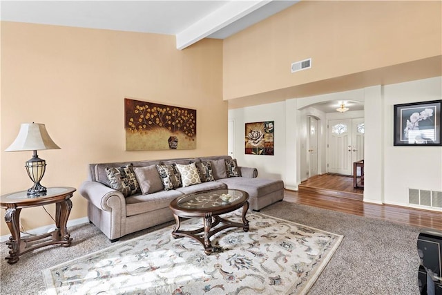 living room featuring beamed ceiling, a towering ceiling, and wood-type flooring