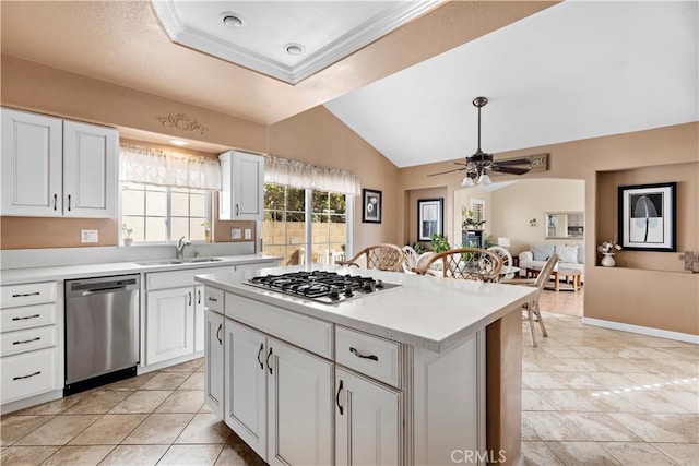 kitchen with appliances with stainless steel finishes, white cabinetry, lofted ceiling, sink, and a center island