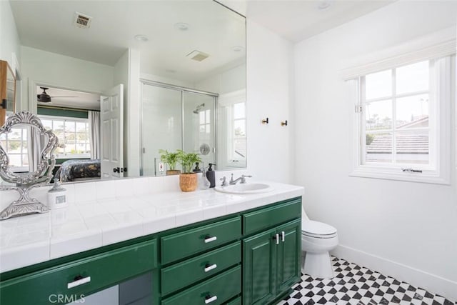 bathroom with baseboards, toilet, visible vents, a shower stall, and vanity