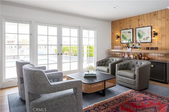 sitting room with crown molding, wood walls, and wood finished floors