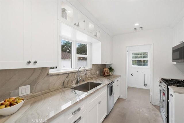 kitchen featuring sink, light stone countertops, white cabinets, and appliances with stainless steel finishes