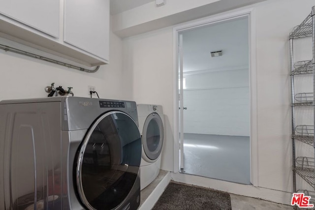 clothes washing area with cabinets and washer and clothes dryer