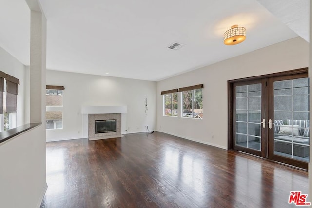 unfurnished living room with french doors, dark hardwood / wood-style floors, and a tile fireplace