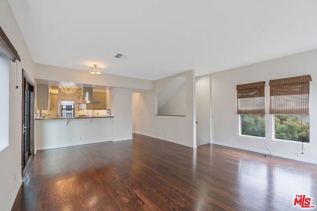 unfurnished living room featuring dark wood-type flooring and a chandelier