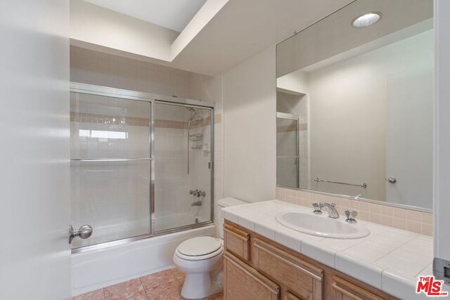 full bathroom with vanity, tile patterned floors, shower / bath combination with glass door, and toilet