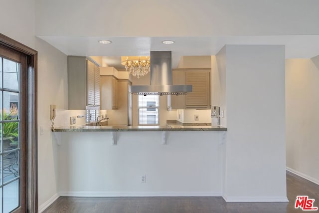 kitchen featuring a chandelier, island exhaust hood, kitchen peninsula, and stone counters