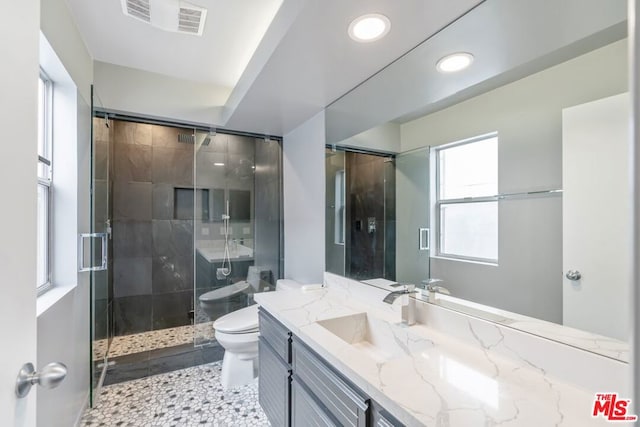 bathroom featuring vanity, a shower with door, and toilet