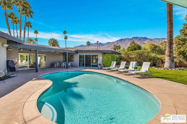 view of pool featuring ceiling fan, a mountain view, and a patio area