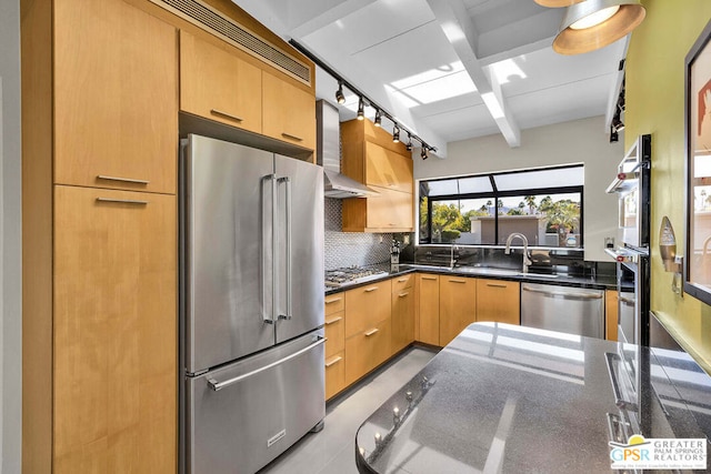 kitchen with light brown cabinetry, sink, appliances with stainless steel finishes, wall chimney range hood, and backsplash