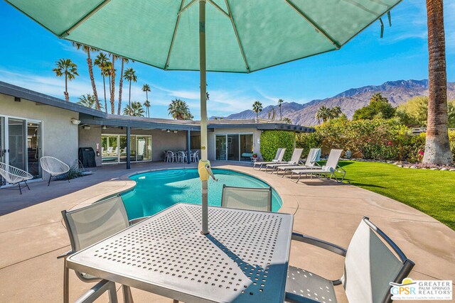 view of pool featuring a mountain view, a lawn, and a patio area