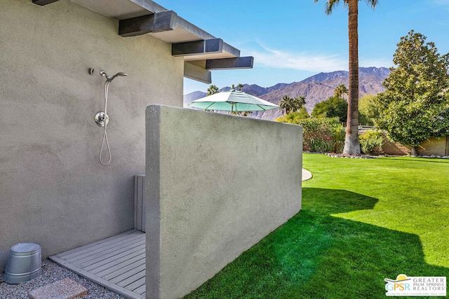 view of side of property with a mountain view and a lawn