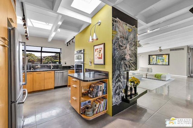 kitchen featuring stainless steel appliances, a skylight, concrete floors, and beamed ceiling