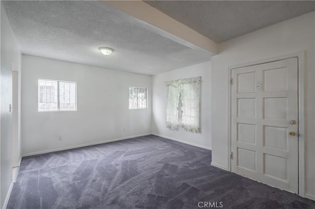 spare room featuring dark colored carpet and a textured ceiling