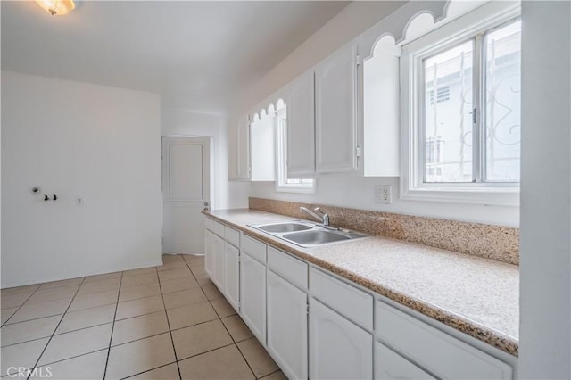 kitchen with sink, light tile patterned floors, and white cabinets