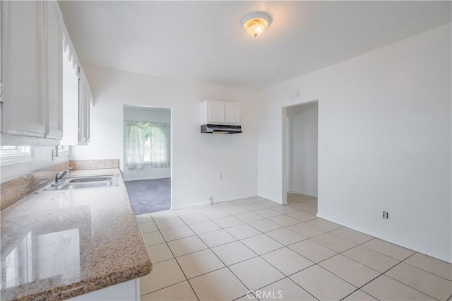 kitchen with sink, light stone countertops, white cabinets, and light tile patterned flooring