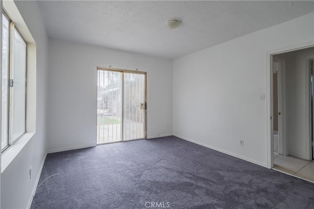 carpeted empty room featuring a textured ceiling