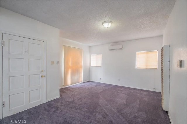 carpeted empty room with plenty of natural light, a textured ceiling, and a wall unit AC