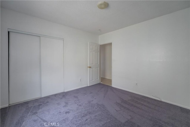 unfurnished bedroom featuring a closet and dark colored carpet