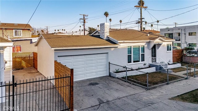 view of front facade featuring driveway, a fenced front yard, roof with shingles, an attached garage, and stucco siding