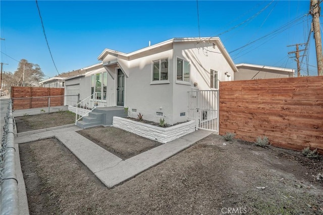 view of front of home with crawl space, fence private yard, a gate, and stucco siding