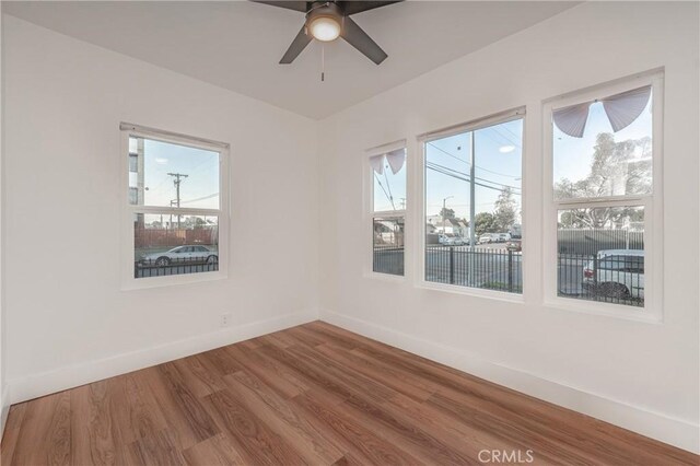 empty room with hardwood / wood-style flooring, ceiling fan, and a wealth of natural light