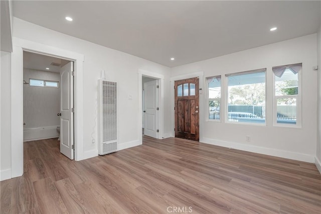 foyer entrance featuring light wood-type flooring, a heating unit, baseboards, and recessed lighting