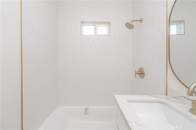 bathroom with tiled shower / bath, plenty of natural light, and vanity