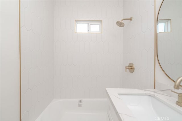 full bath with shower / bathing tub combination, a sink, and a healthy amount of sunlight