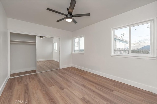 unfurnished bedroom with a closet, wood finished floors, a ceiling fan, and baseboards