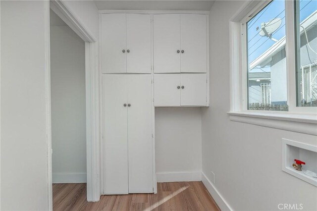 washroom with washer hookup, light hardwood / wood-style floors, and cabinets