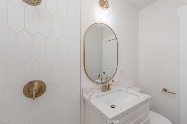 bathroom featuring toilet, tiled shower, and vanity