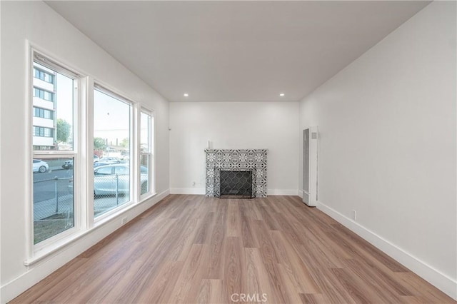 unfurnished living room featuring recessed lighting, a fireplace, light wood-style flooring, and baseboards