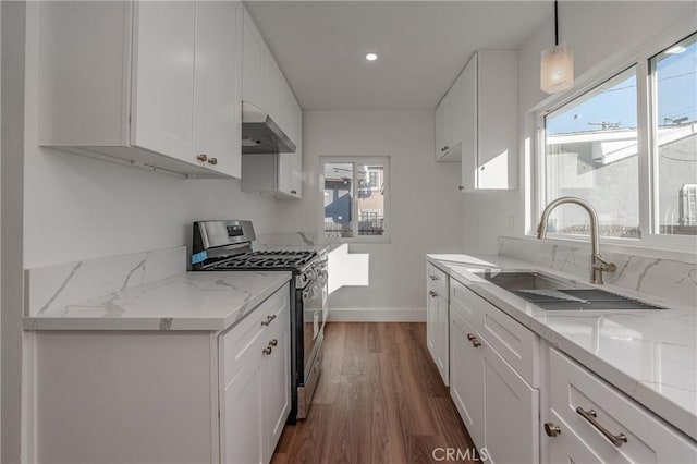 kitchen with dark wood finished floors, white cabinetry, a sink, stainless steel gas range oven, and wall chimney exhaust hood