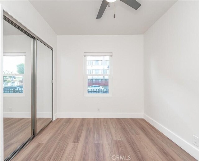 unfurnished bedroom with multiple windows, a closet, ceiling fan, and light hardwood / wood-style flooring