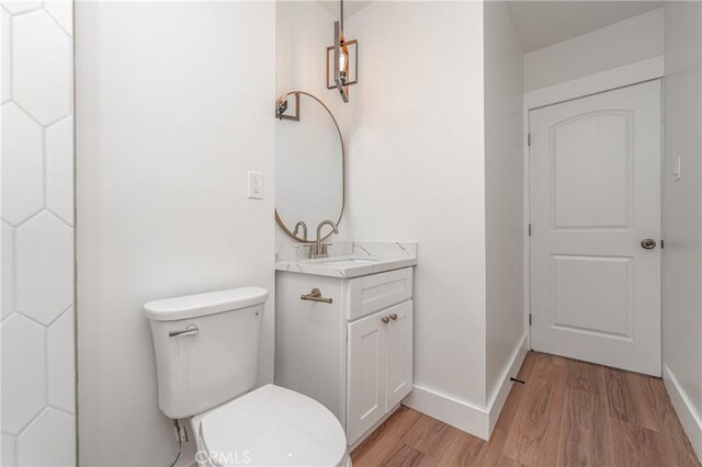 bathroom with hardwood / wood-style flooring, vanity, and toilet