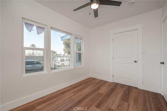 spare room with a ceiling fan, baseboards, and wood finished floors