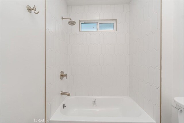 bathroom featuring tiled shower / bath and toilet