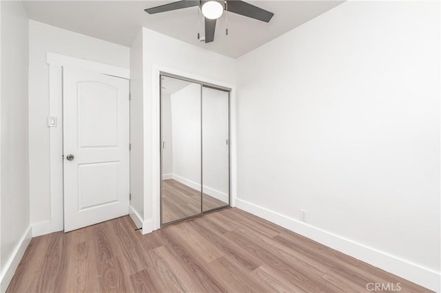 unfurnished bedroom with light wood-style floors, a closet, ceiling fan, and baseboards