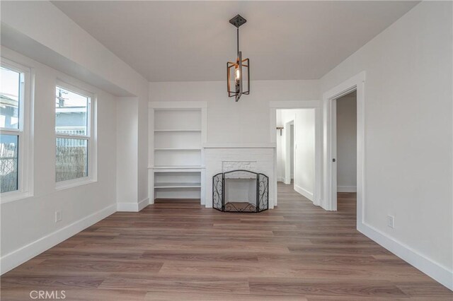 unfurnished living room with hardwood / wood-style flooring, built in features, and a fireplace